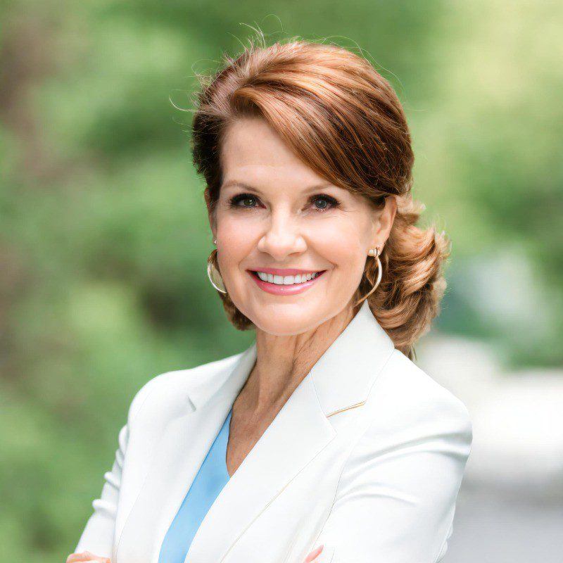 Confident woman smiling outdoors in professional attire.