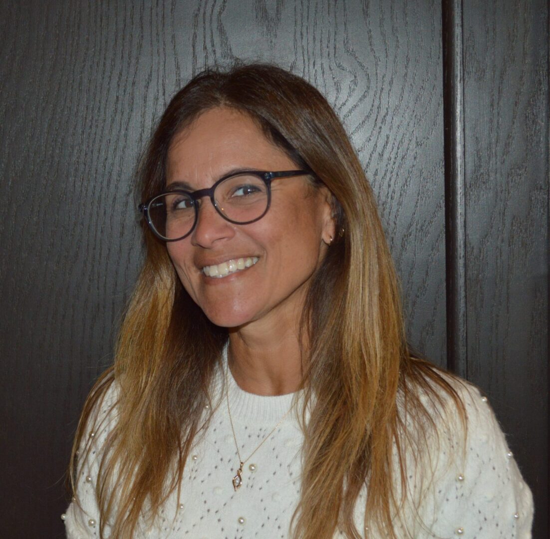 Smiling woman wearing glasses, white sweater